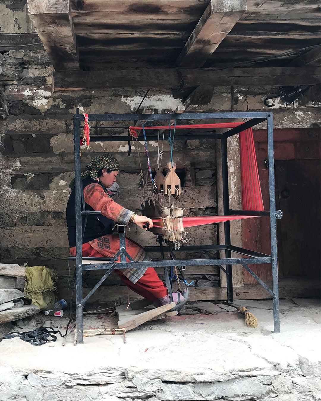 Himachali woman hand weaving on a loom in her house